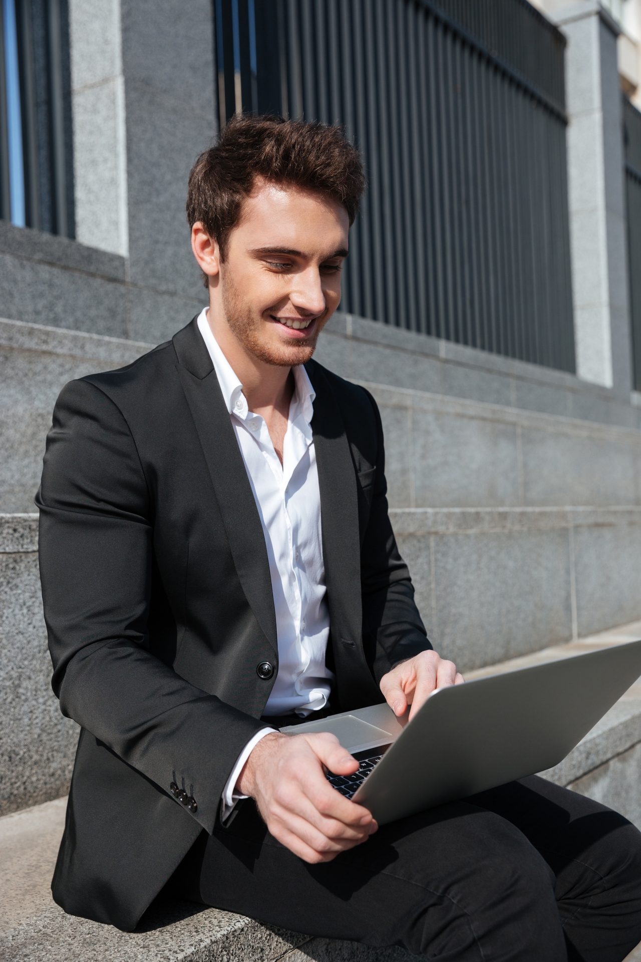 Joven empresario sonriendo mientras usa una laptop